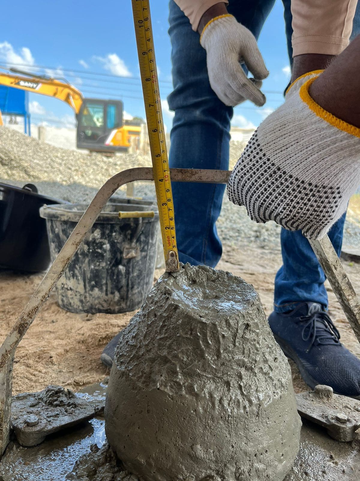 Technician measuring the slump of fresh concrete with a tape beside the slump cone