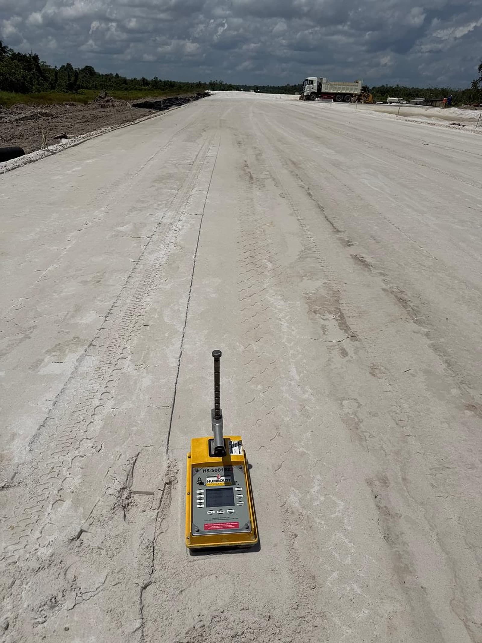 Nuclear density gauge on a long stretch of compacted road base with a tipper truck in the distance