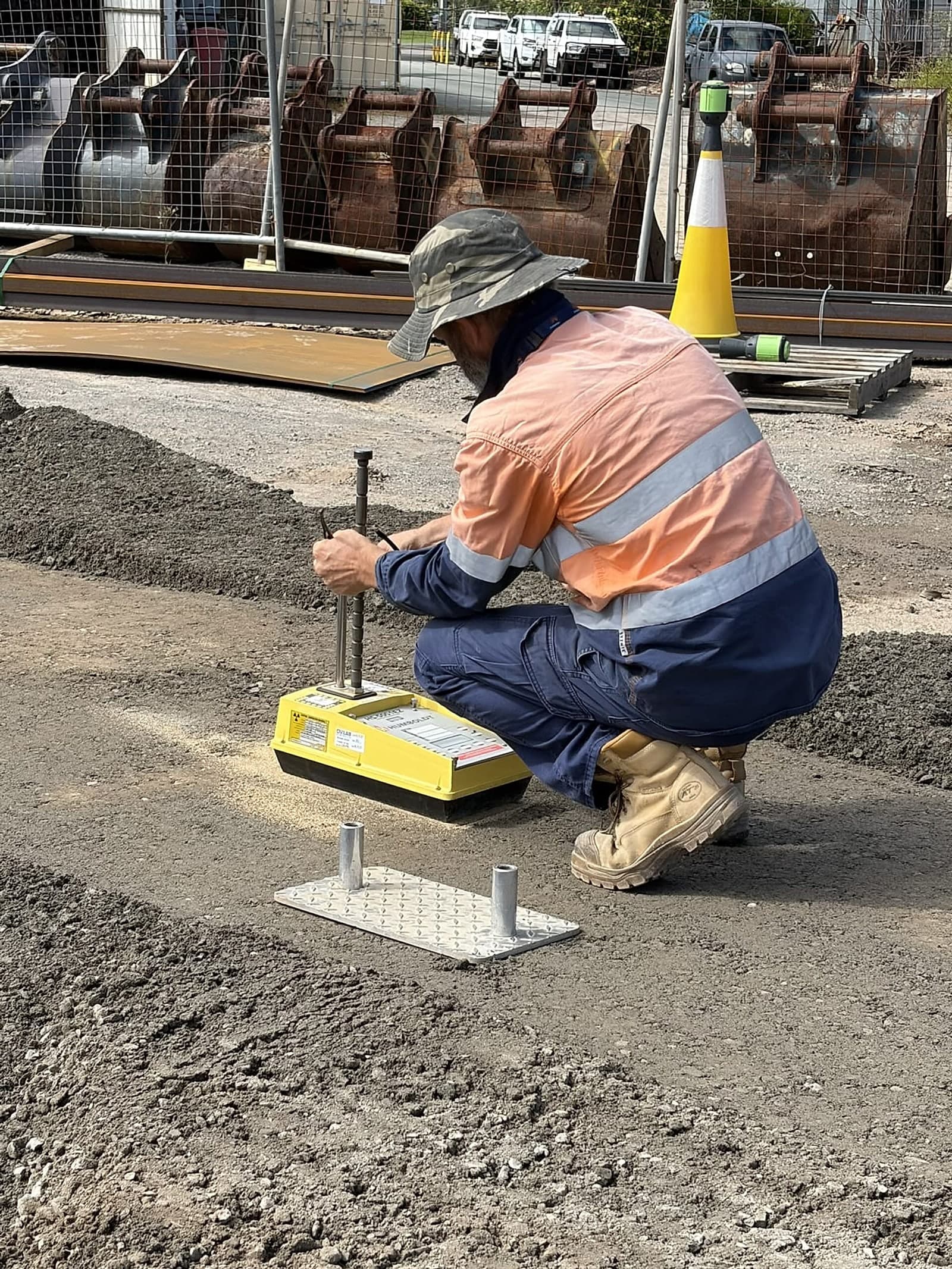 Technician lowering the probe rod of a nuclear density gauge beside its reference plate
