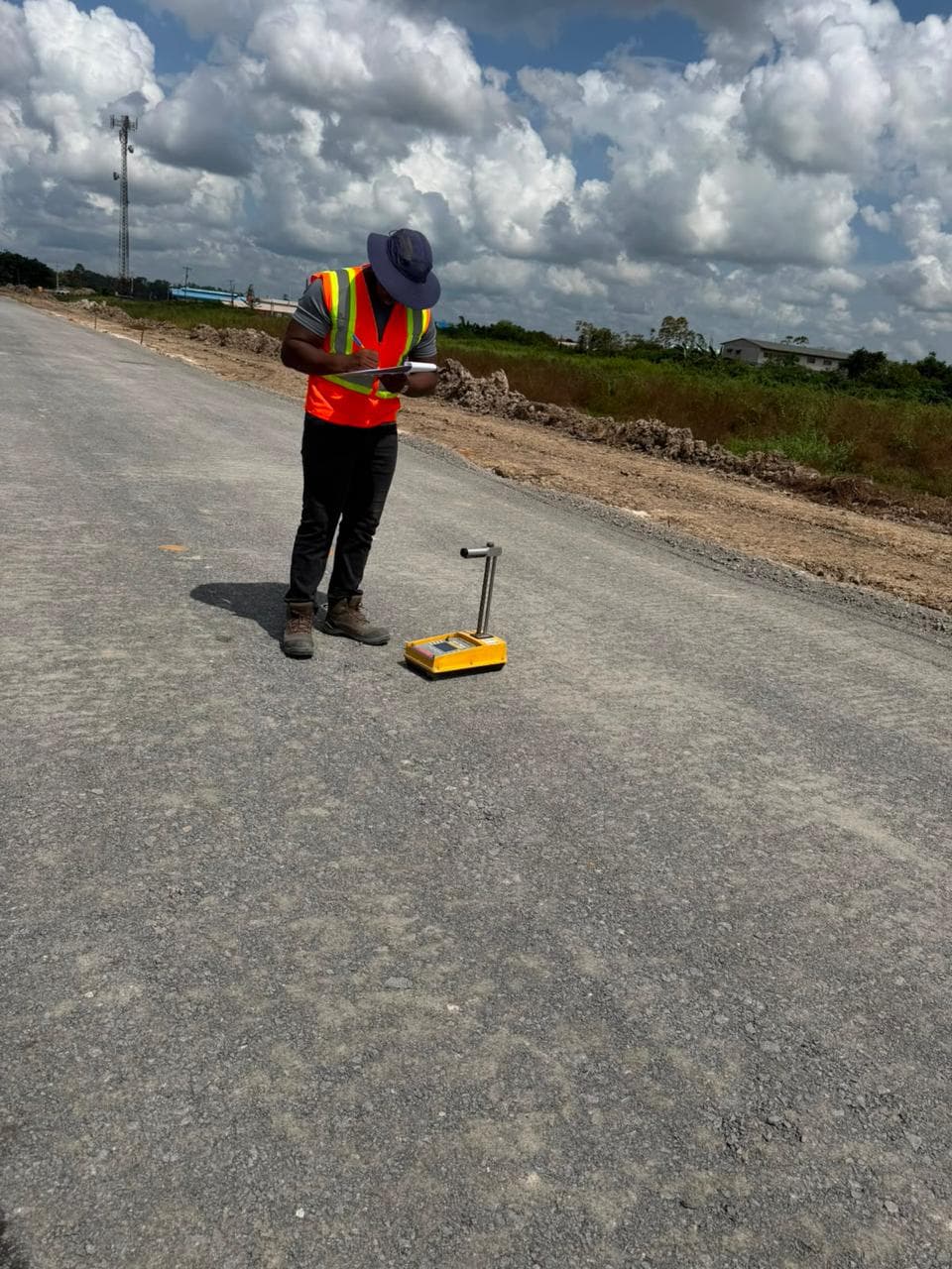 Inspector recording results beside a nuclear density gauge on a compacted road base