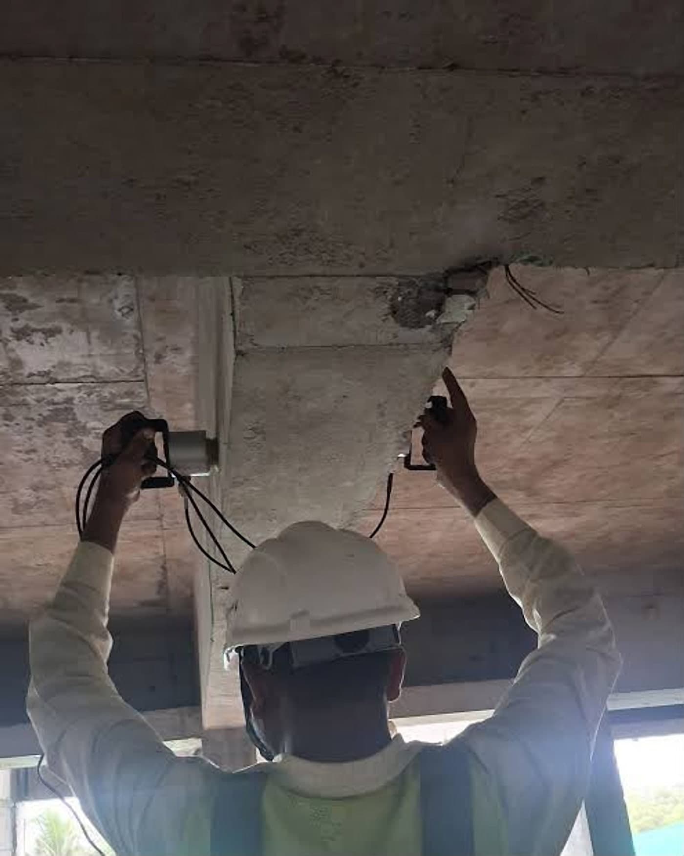 Technician positioning two ultrasonic transducers on either side of a concrete member